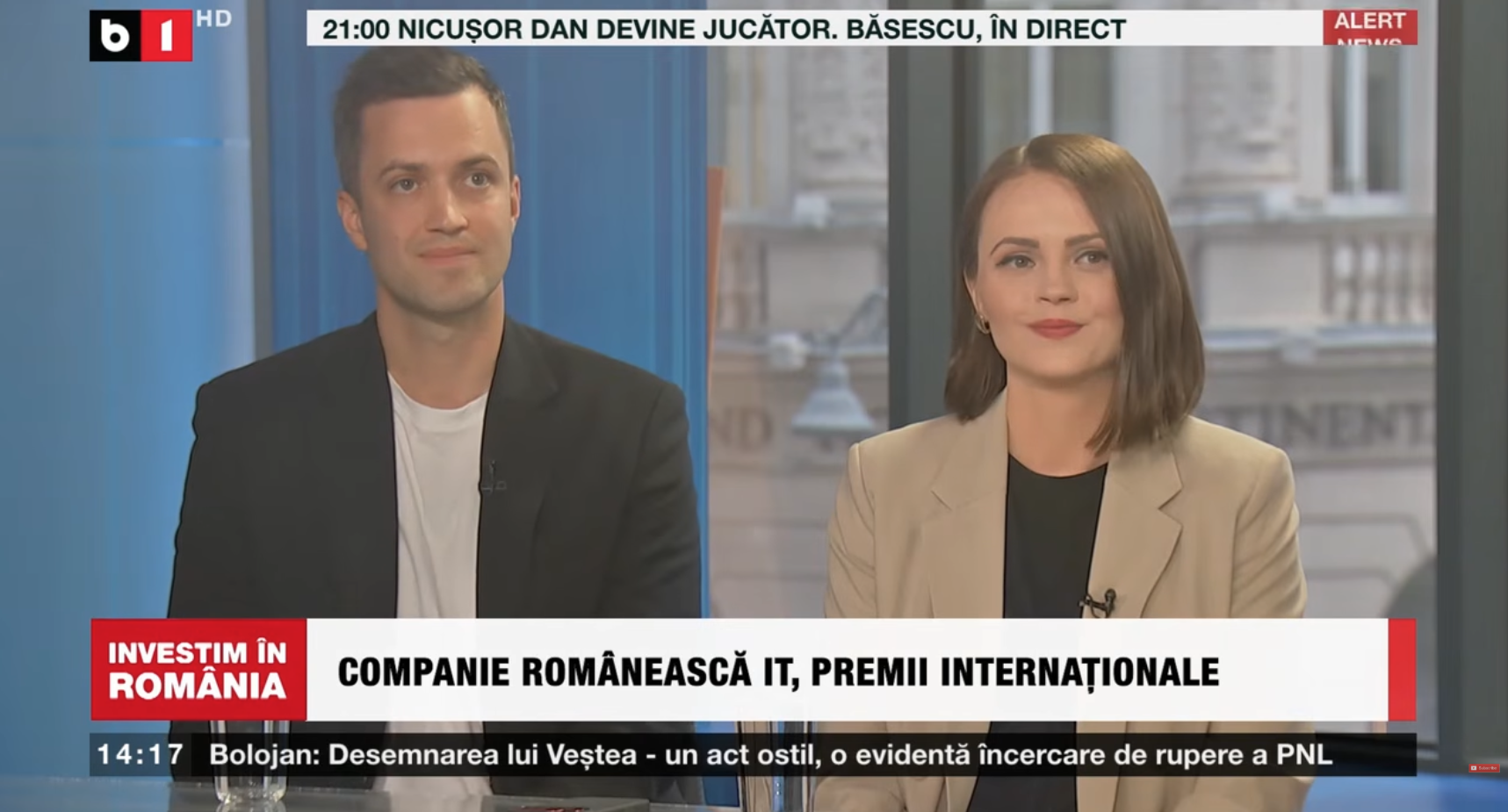 Adrian Florian and Georgina Lupu Florian smiling in the B1 TV studio at the end of "Investim în România", under the caption "Companie românească IT, premii internaționale" (Romanian IT company, international awards)