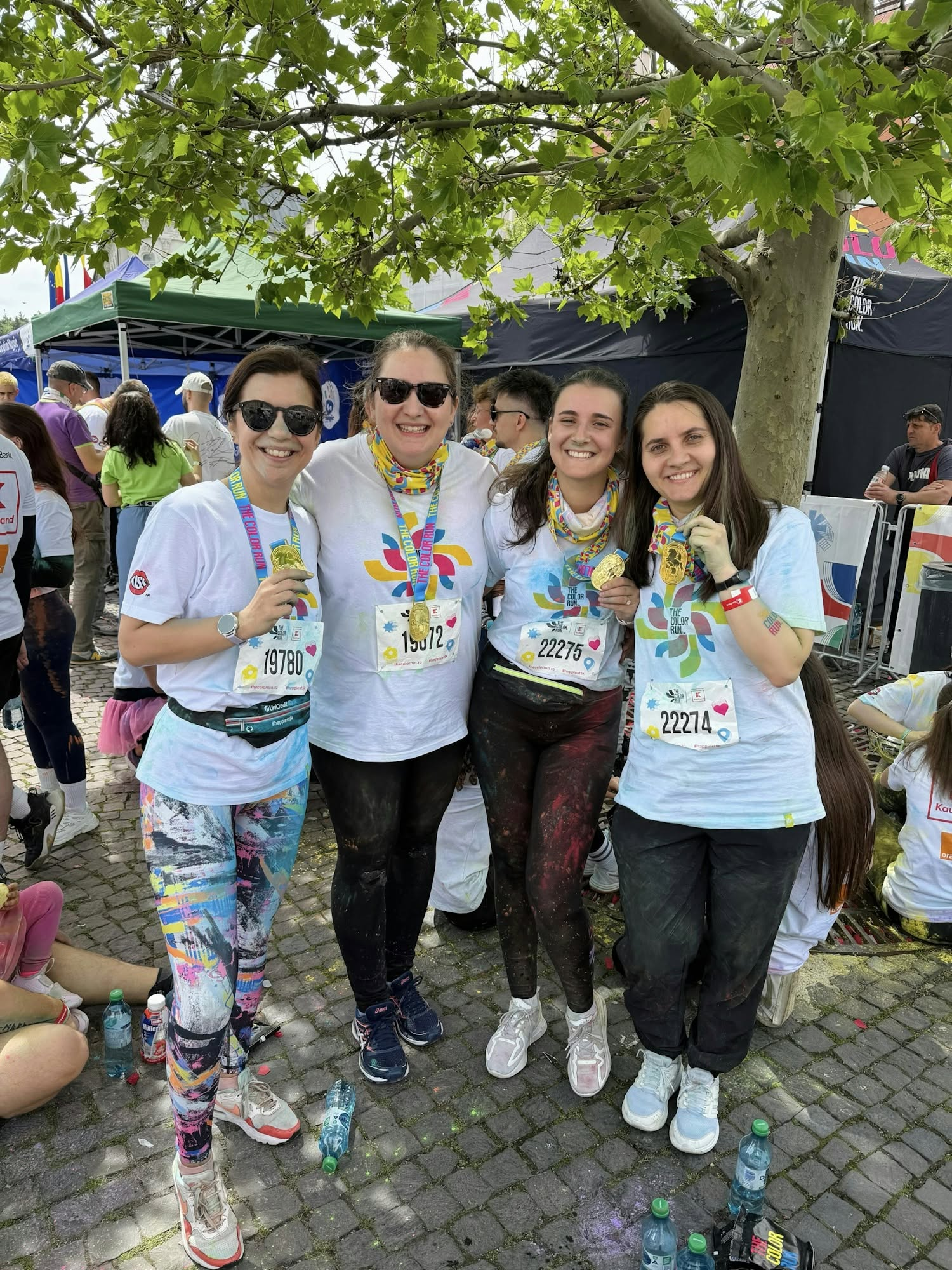 Members of the Wolfpack Digital team celebrate finishing The Color Run together, holding up their medals in colour-splattered race t-shirts.