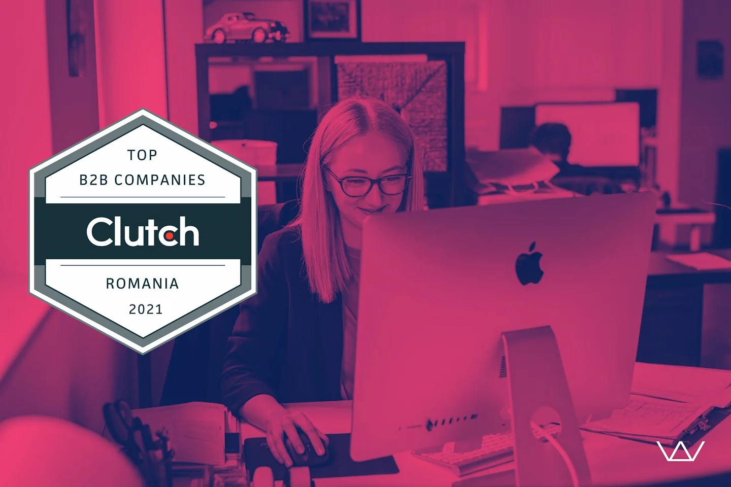 Photo of a person working at an iMac with a Clutch 'Top B2B Companies Romania 2021' badge, recognizing Wolfpack Digital as a top B2B company