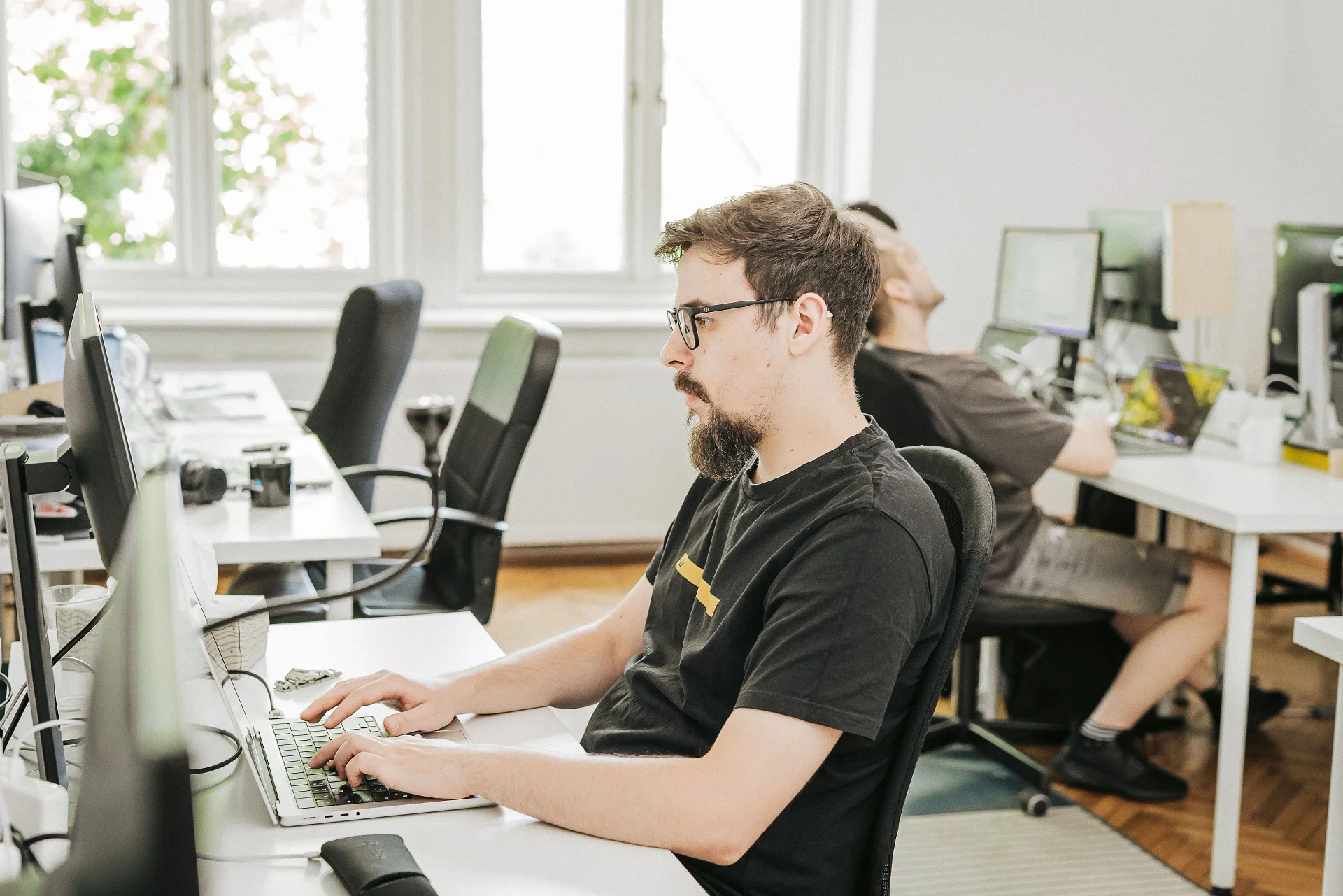Wolfpack Digital developer working at a desk with monitors in an open-plan office