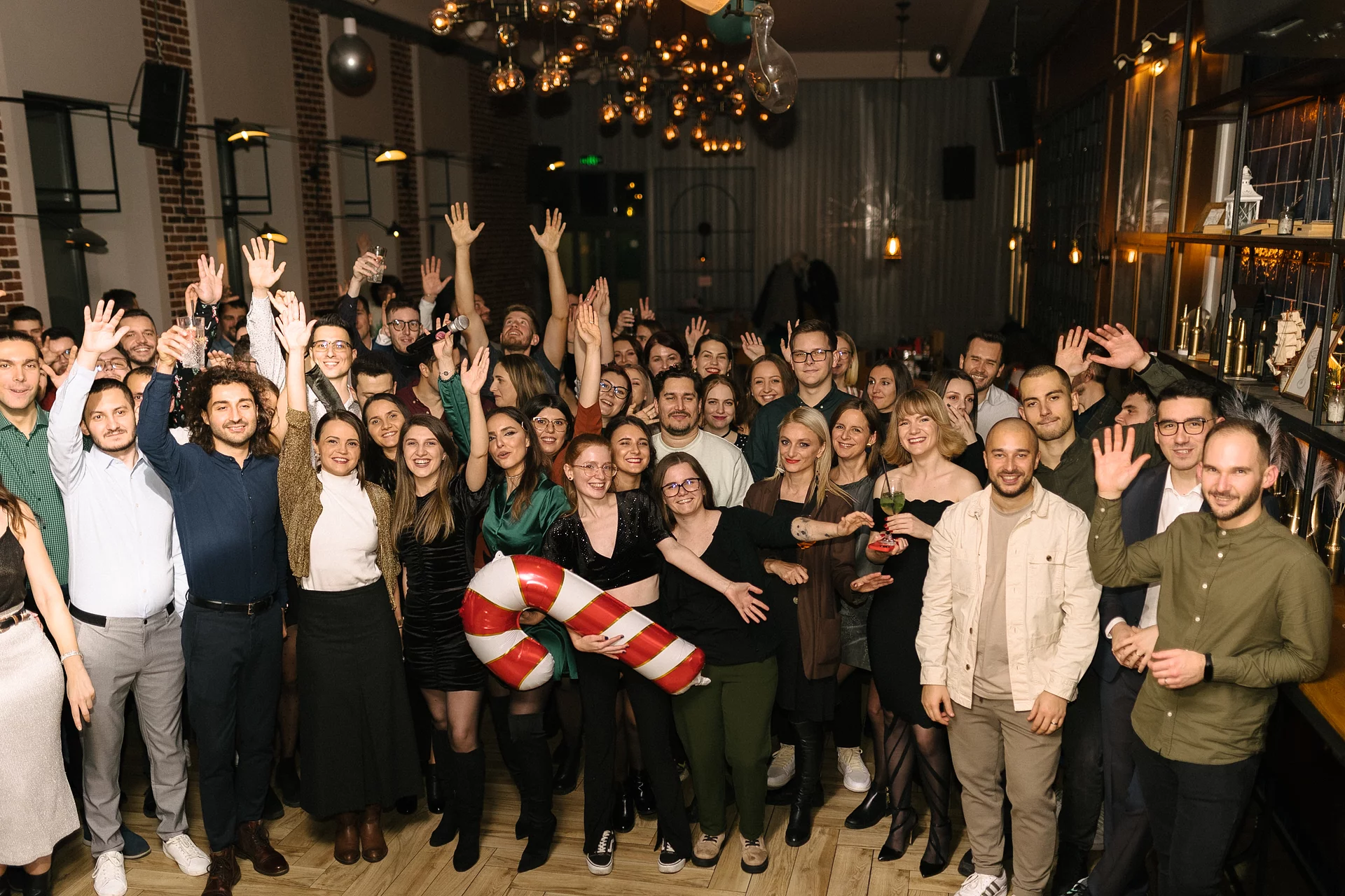 The full Wolfpack Digital team cheering with raised hands at their festive Christmas dinner celebration in 2023